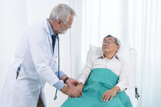 Senior doctor holding the hands of elderly patient man