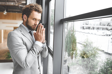 portrait of caucasian businessman standing at window in office and praying