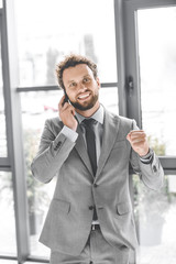 portrait of young excited businessman talking on smartphone in office