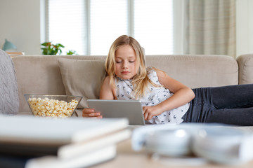 Cute girl using digital tablet in living room