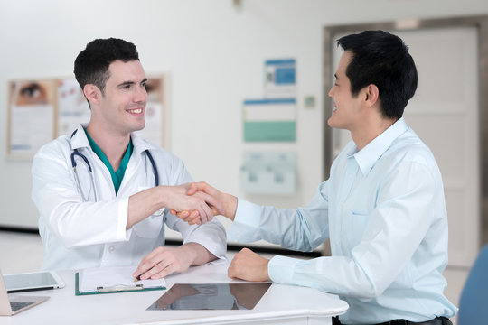 Young doctor shaking the hand of middle-aged patient male