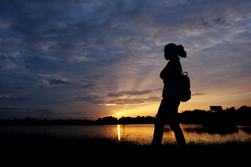 Silhouette of girl stand near at the river  at the sunset