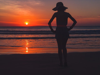 Lonely girl looking at the ocean / sea view at sunset time.