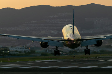 夕陽に包まれ降りてくる飛行機