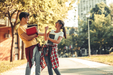 Young student couple going to college lecture. They walk through university campus and laughing....