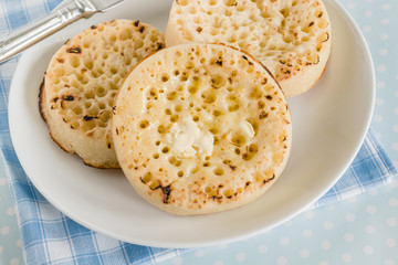 Hot toasted English crumpets spread with melting butter