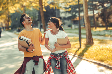 Young student couple going to college class.They walks trough university campus and laughing.Autumn.