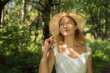 girl in a straw hat in the forest on a sunny day