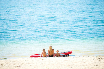 Family sits on the beach and rests after skiing on paddle board .Water sports , active lifestyle.