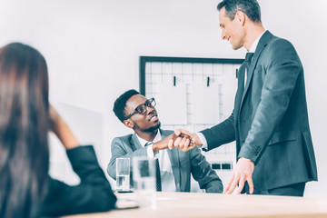 handsome multiethnic businessmen shaking hands in modern office