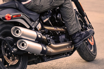 Obraz na płótnie Canvas The biker rides a motorcycle. Rear view. Exhaust pipe