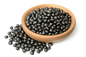 uncooked black beans in the wooden plate, isolated on the white background