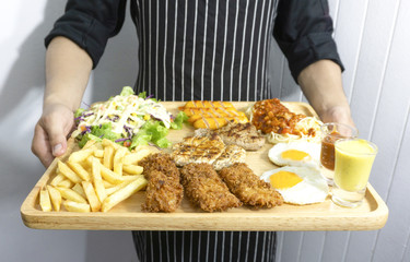 Midsection of male chef carrying beef,chicken,Fried fish,Roasted sausage set steak at restaurant, close up view.