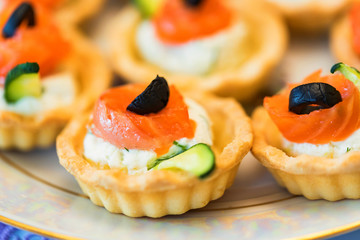 Tartlets with cheese, salmon and olives close