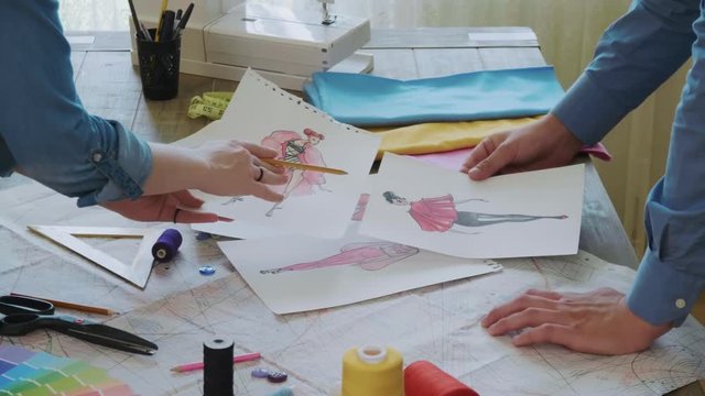 Small team of fashion designers choosing sketches for the new dress