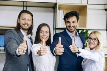 Successful young business people showing thumbs up sign