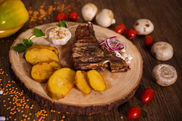 steak t-bone on wooden backing and baked potatoes