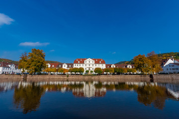 Fototapeta na wymiar Beautiful panoramic view of a row of baroque houses and the Huguenot Museum in the middle, mirrored on the water surface of the harbour basin on a nice autumn day in Bad Karlshafen, Germany.