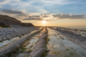 Setting Sun at Kilve Beach, Somerset, with Limestone (Blue Lias) wave cut platform, with rock pools 