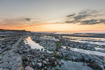 Sunset at Kilve Beach, Somerset, with Limestone (Blue Lias) wave cut platform, with rock pools 