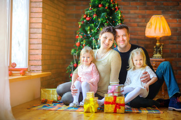 Happy family with gifts on Christmas morning sitting on the floor near the Christmas tree