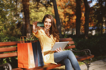 Young woman online shopping via digital tablet in the park