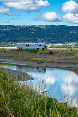 Old retro abandoned bus sits along in a marsh along the Homer Spit in the Kachemak Bay Area of Alaska. Reflection in the water