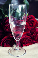 A glass of champagne and red roses