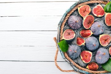 Figs in a wooden box on a white wooden background. Free space for text. Top view.