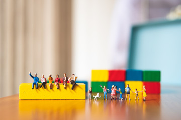 Miniature people, adult and children with wooden color background using as business, family and education concept