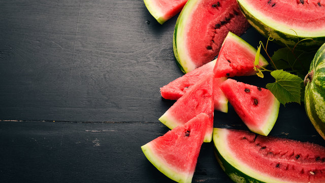 Fresh watermelon Fruits. Melon. On a black wooden background. Free space for text. Top view.
