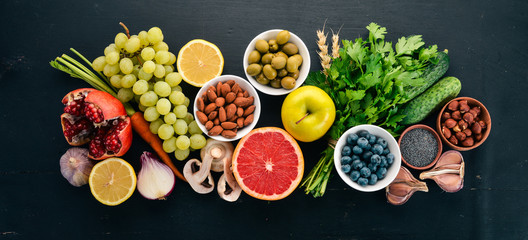 Healthy food clean eating selection: Vegetables, fruits, nuts, berries and mushrooms, parsley, spices. On a black background. Free space for text.