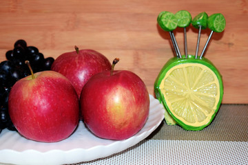 Still life of fresh fruit grapes, apples, apricots and pears on a white plate. Decorative wooden background. Ripe juicy sweet fruits. Vegetarian diet food.