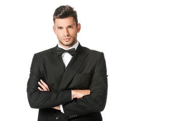 handsome young man in black suit with bowtie with crossed arms isolated on white