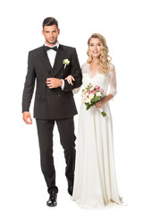 happy young bride and groom walking together and looking at camera isolated on white