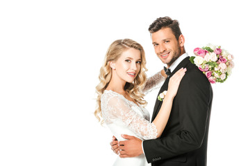happy newlyweds embracing and looking at camera isolated on white