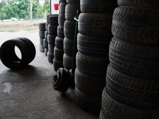 Obraz premium Used car tires stacked in piles at junkyard. Old wheels recycling and utilization concepr