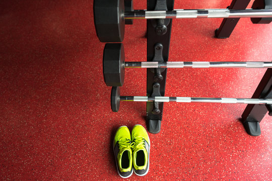 Fitness rod with weights and sport shoes in gym
