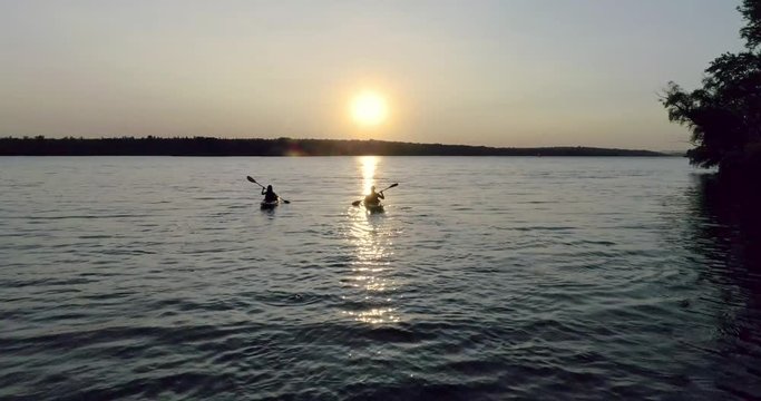 Two kayaks with people on the river on the scenic sunset