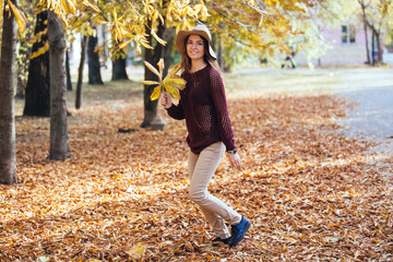 Happy young woman having fun time in autumn outdoors. Cheerful smiling girl jumping running in the...