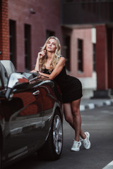 beautiful girl posing next to a beautiful cabriolet car on a beautiful building background