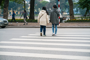 People walking across a street in Hanoi, Vietnam. Closeup