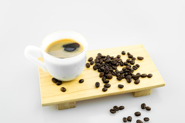 White Cup of hot coffee with coffee beans on wooden board and Gray background with copy space.