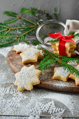 Fototapeta na wymiar Preparation for new year 2019: pastry biscuits in the form of stars with powdered sugar, decorated red bow and branches of a Christmas tree. the table with powdered sugar in the form of a snowflake