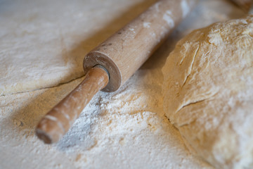 Dough and wooden rolling pin on the kitchen table