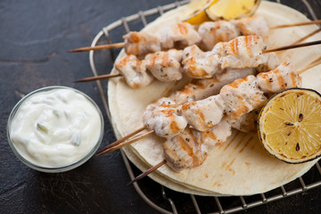 Closeup of greek souvlaki or traditional wooden skewers with chicken meat, tortilla wraps and tzatziki sauce, studio shot
