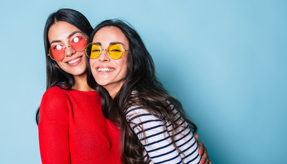 Like a sisters! Two beautiful young girl friends in sunglasses posing with smile and have a fun on...