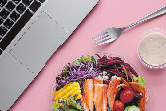 Fresh salad vegetables with computer laptop at workplace for diet and heathy lunch eating concept