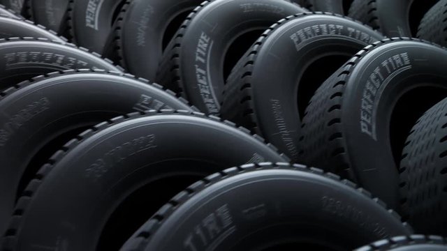 Endless, seamless loop of a stack of new car tires in soft, dim spotlight. 4K HD