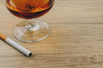 close up of a glass of brandy and cigarette on the wooden table
